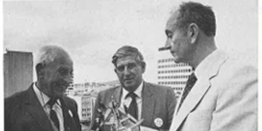 An old black and white newspaper photo of three men in suits.