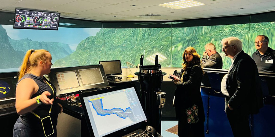 A woman talks to some older people in business attire in the maritime simulator.