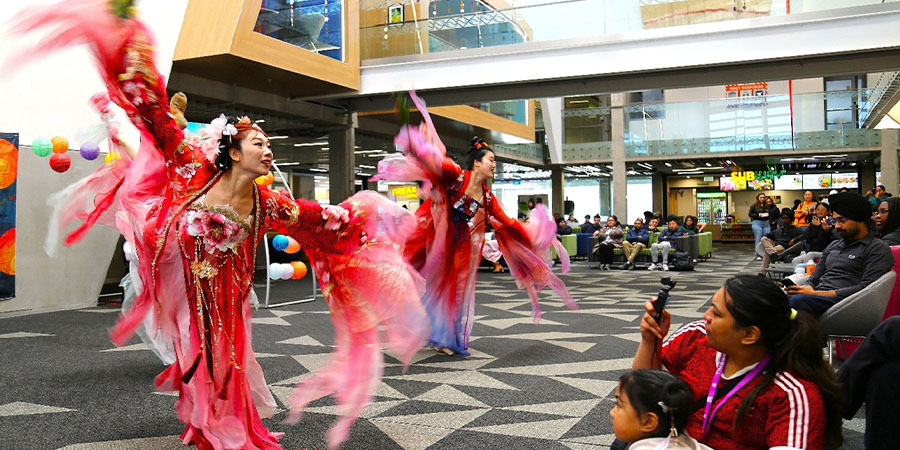Dancers in traditional Chinese dance attire perform in front of an audience.