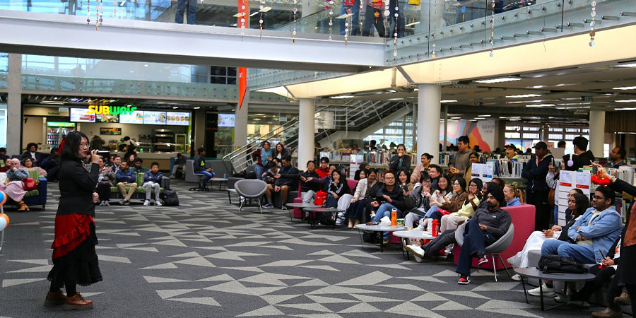 A woman sings a song in front of an audience in a library.