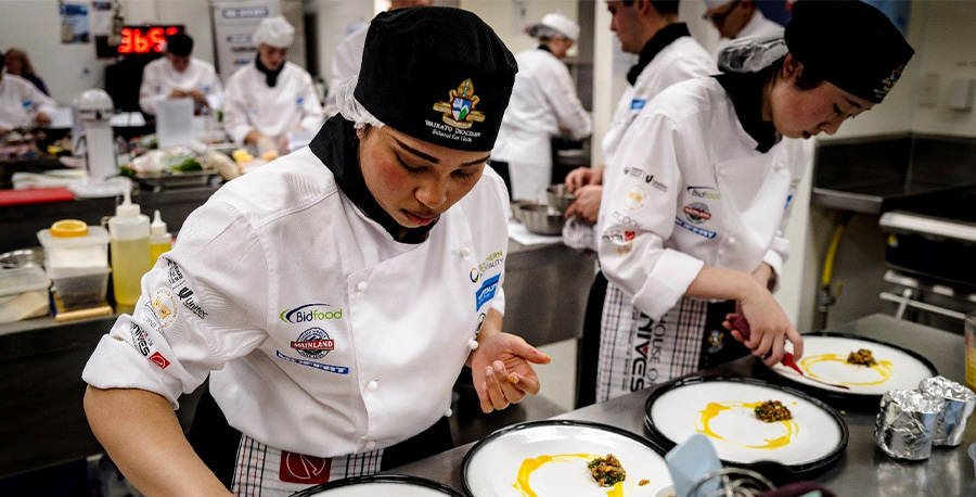 Students in a kitchen work on dishes.