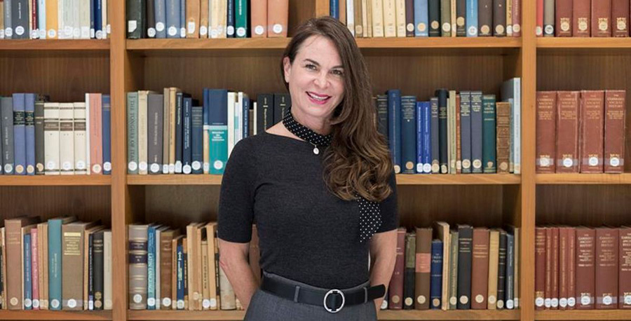 Associate Professor Renata Jadresin-Milic smiles in front of a bookcase.