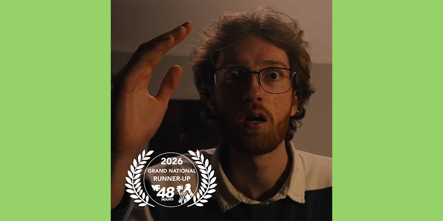 A man with a beard and glasses looks past the camera with an expression of shock on his face.
