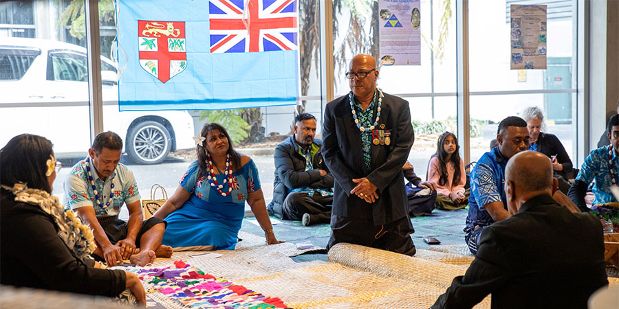 A group of people in traditional Fijian attire participate in a Kava ceremony.