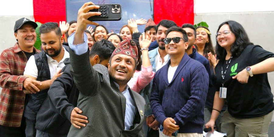 A large group of people gather in tight together to pose for a selfie.