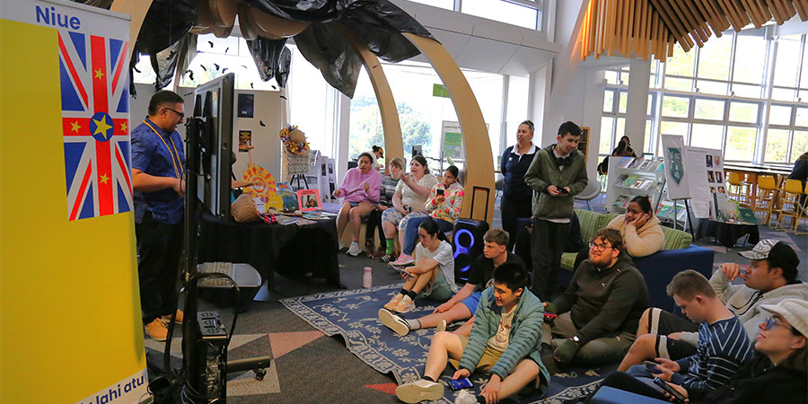People gather in a light-filled open air space to listen to a speech.