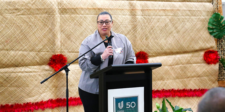 Pacific Business Trust CEO Tracey Alenepi stands at a lectern giving a speech.