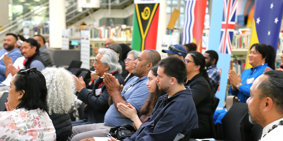 A large group of people sit in rows listening to a speech.