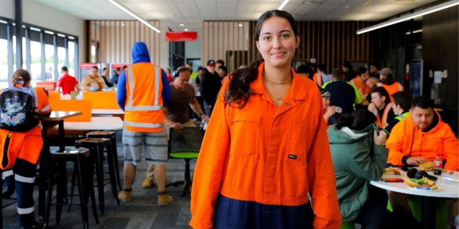 A young woman in high-vis workwear smiles for the camera in an industry event.